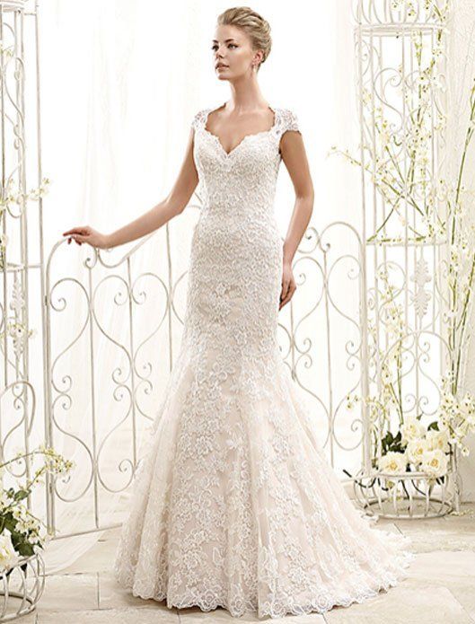 Bride in a white lace wedding gown standing in a bright, elegant setting