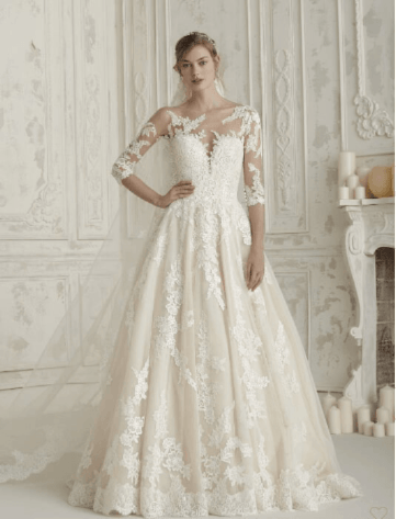 Bride in an ivory lace wedding gown standing in a white ornate room.