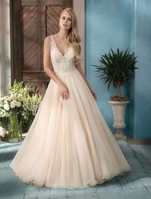 Woman in a cream tulle gown standing in a studio with blue walls and flowers