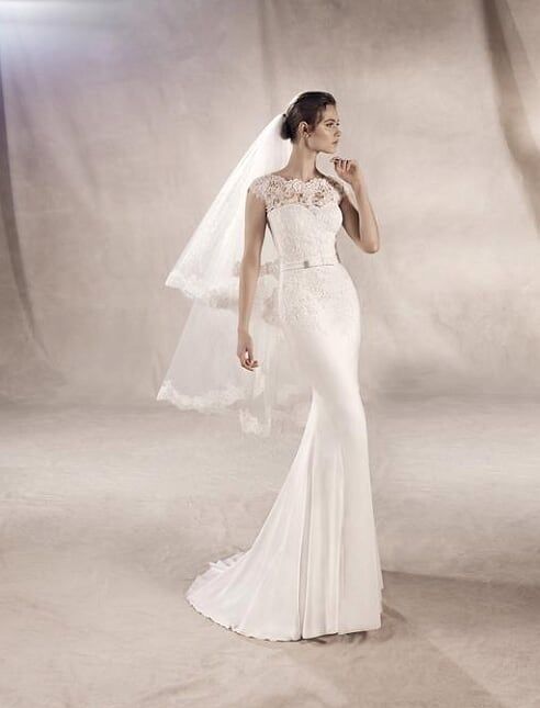 Bride in a white strapless wedding gown with veil, standing in a studio backdrop and looking to the side