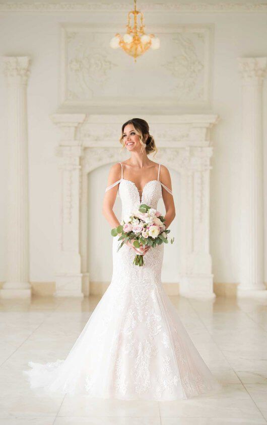 Bride in a white wedding gown holding a bouquet in a bright ornate room