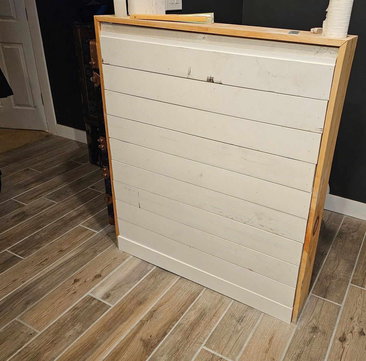A white wooden shelf is sitting on a wooden floor.
