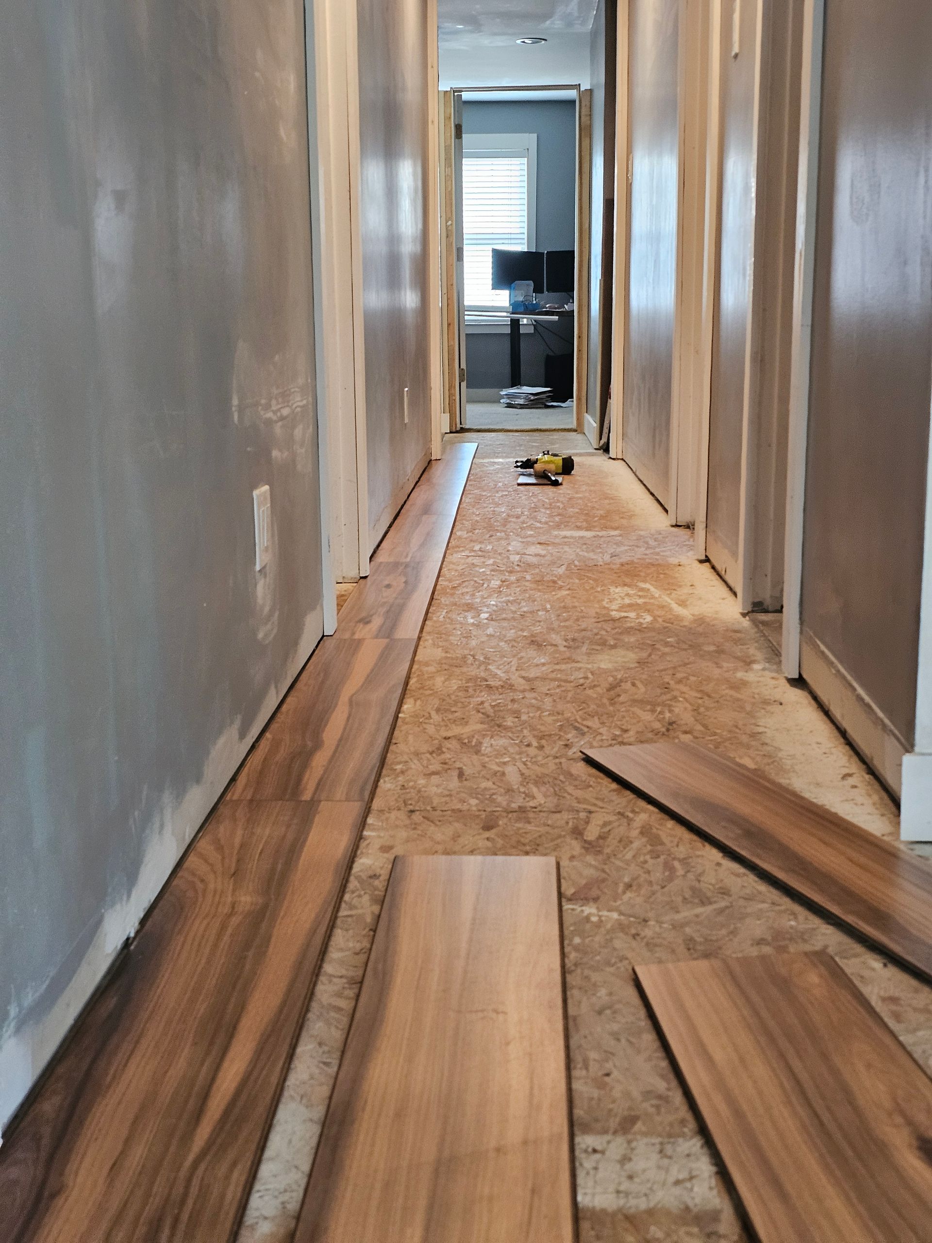 A hallway with wooden floors being installed in a house