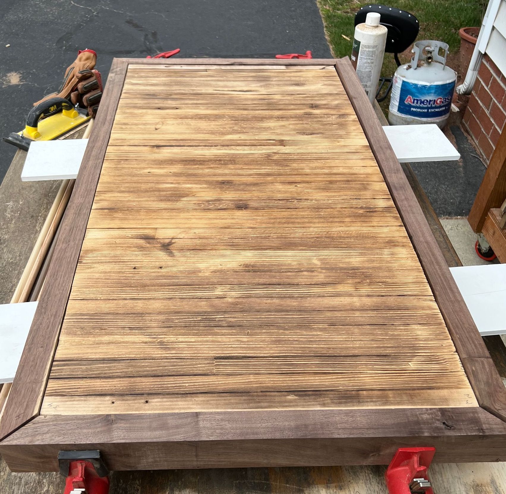 A wooden table with a propane tank in the background