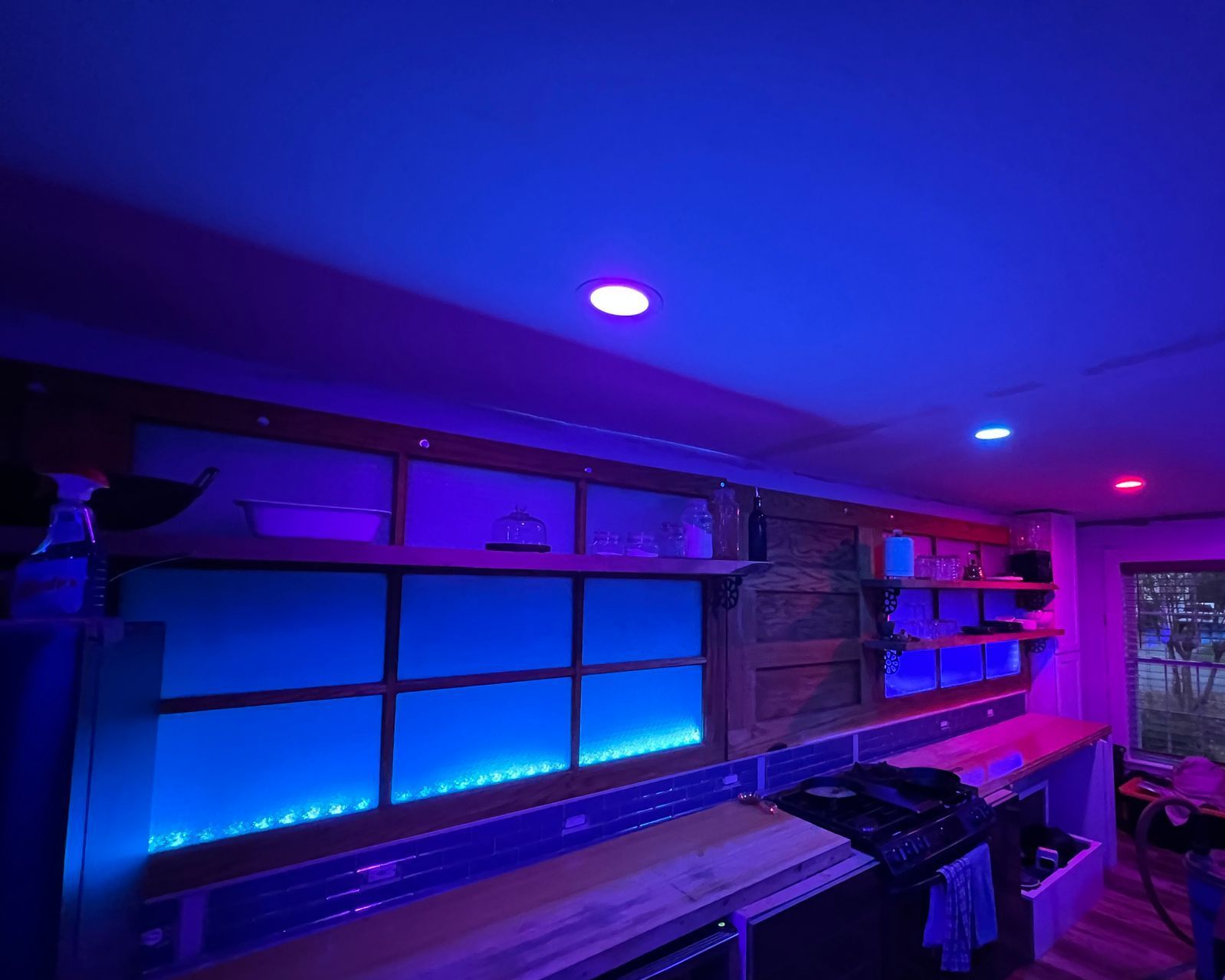 A kitchen with purple and blue lights on the ceiling.