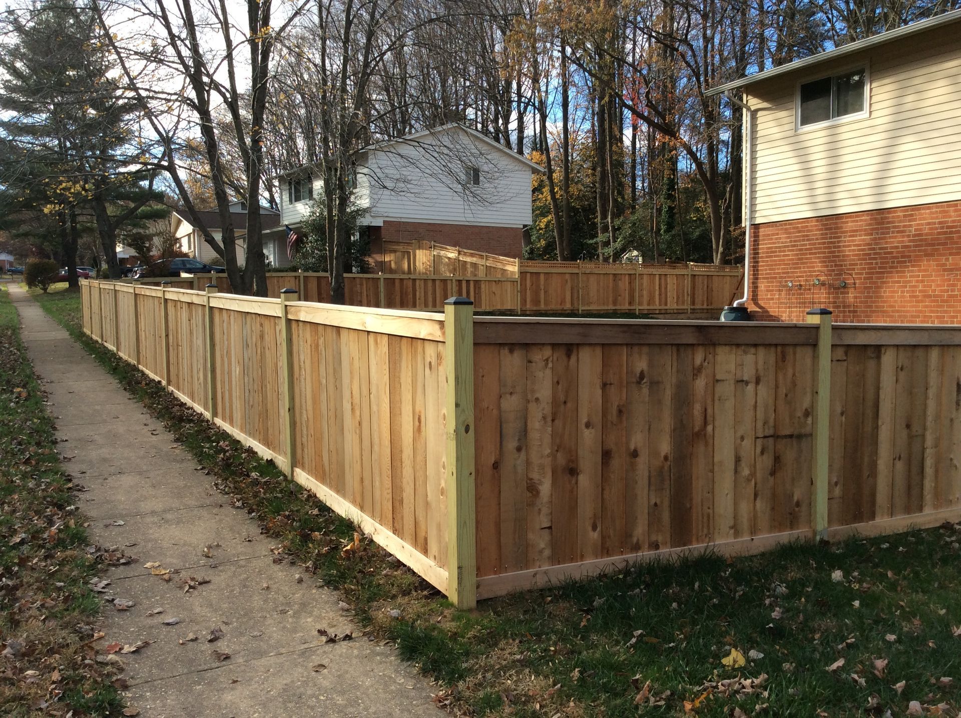 A wooden fence along a sidewalk next to a house.
