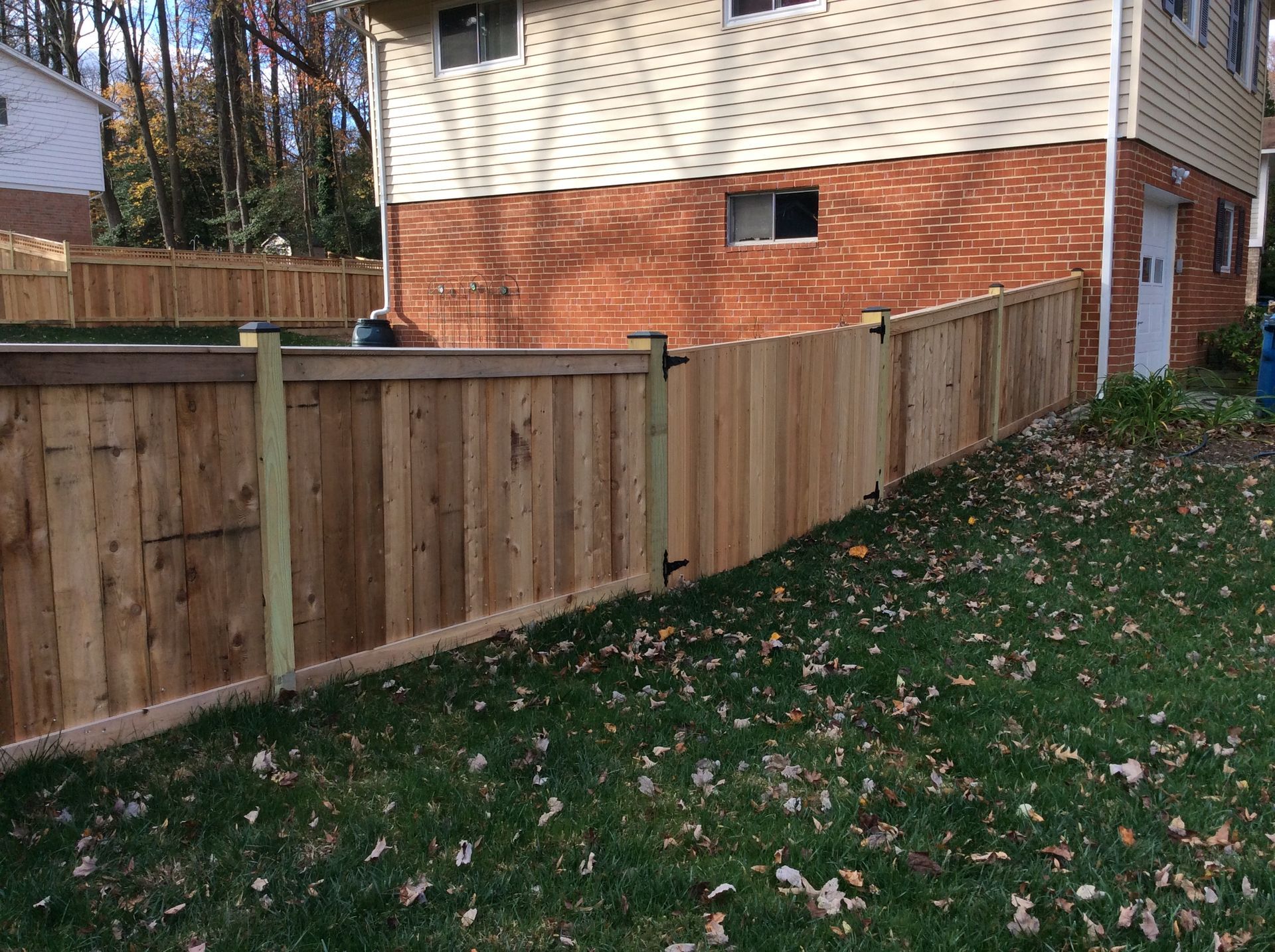 A wooden fence is in front of a brick house.