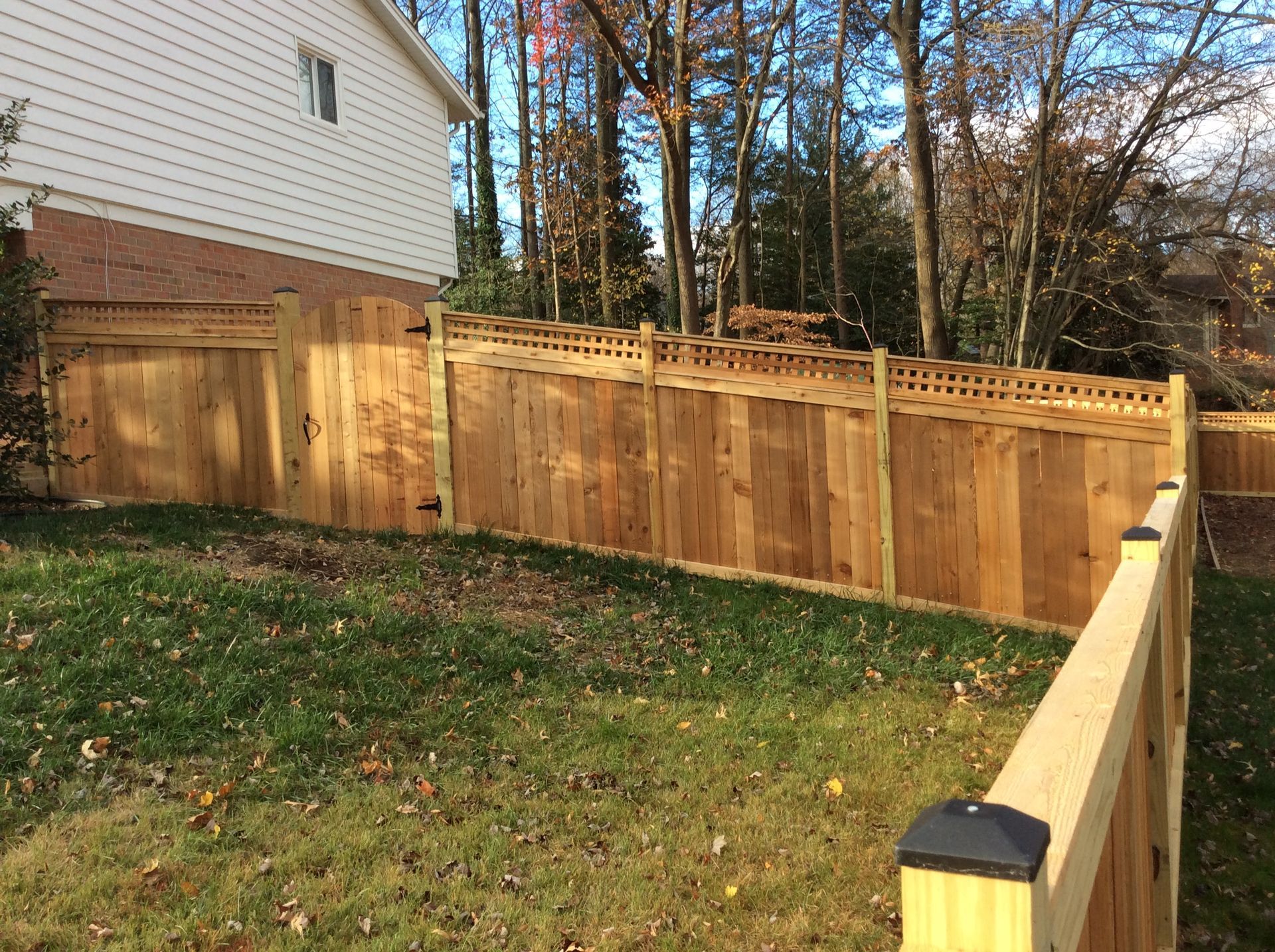 A wooden fence is in the backyard of a house.