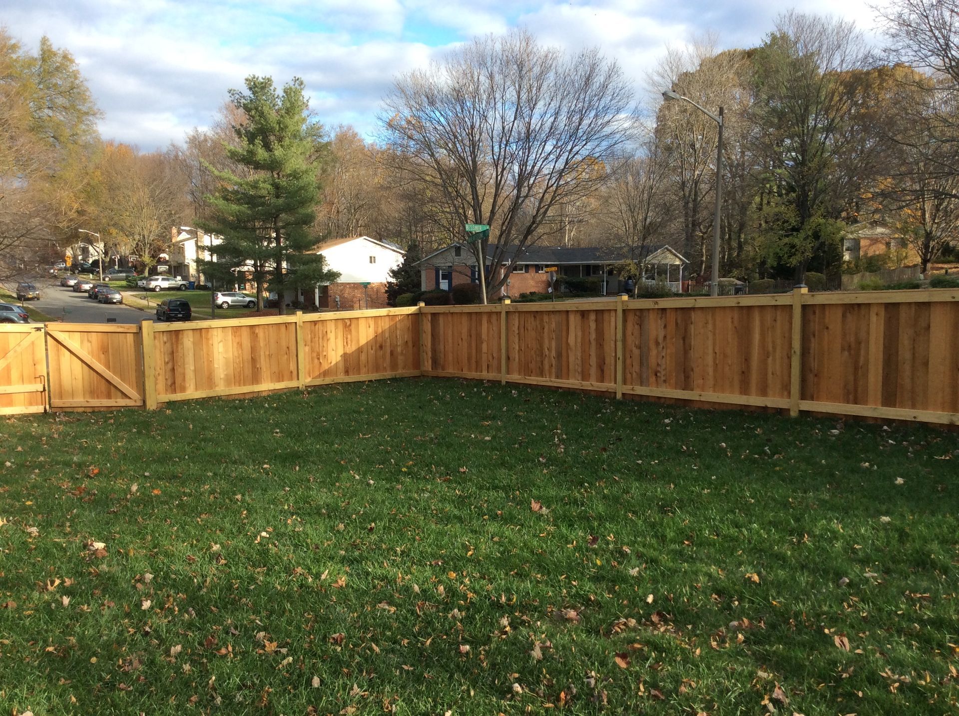 A wooden fence surrounds a lush green lawn in a backyard.