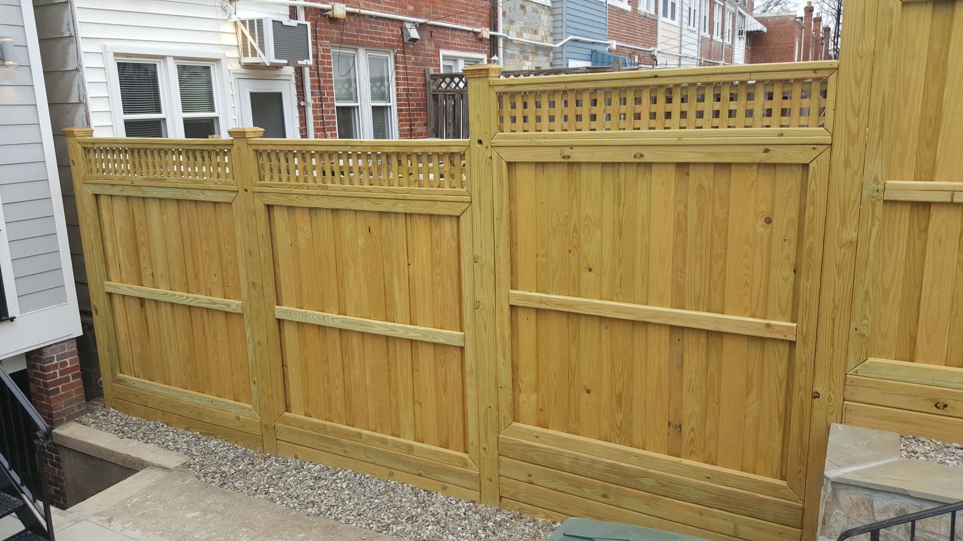 A wooden fence is sitting in front of a brick house.