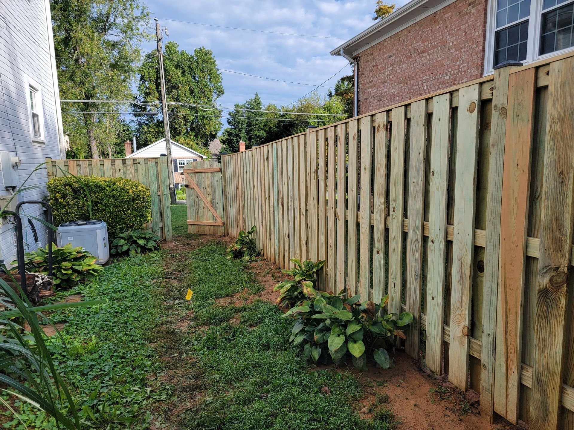 A wooden fence is in the backyard of a house.
