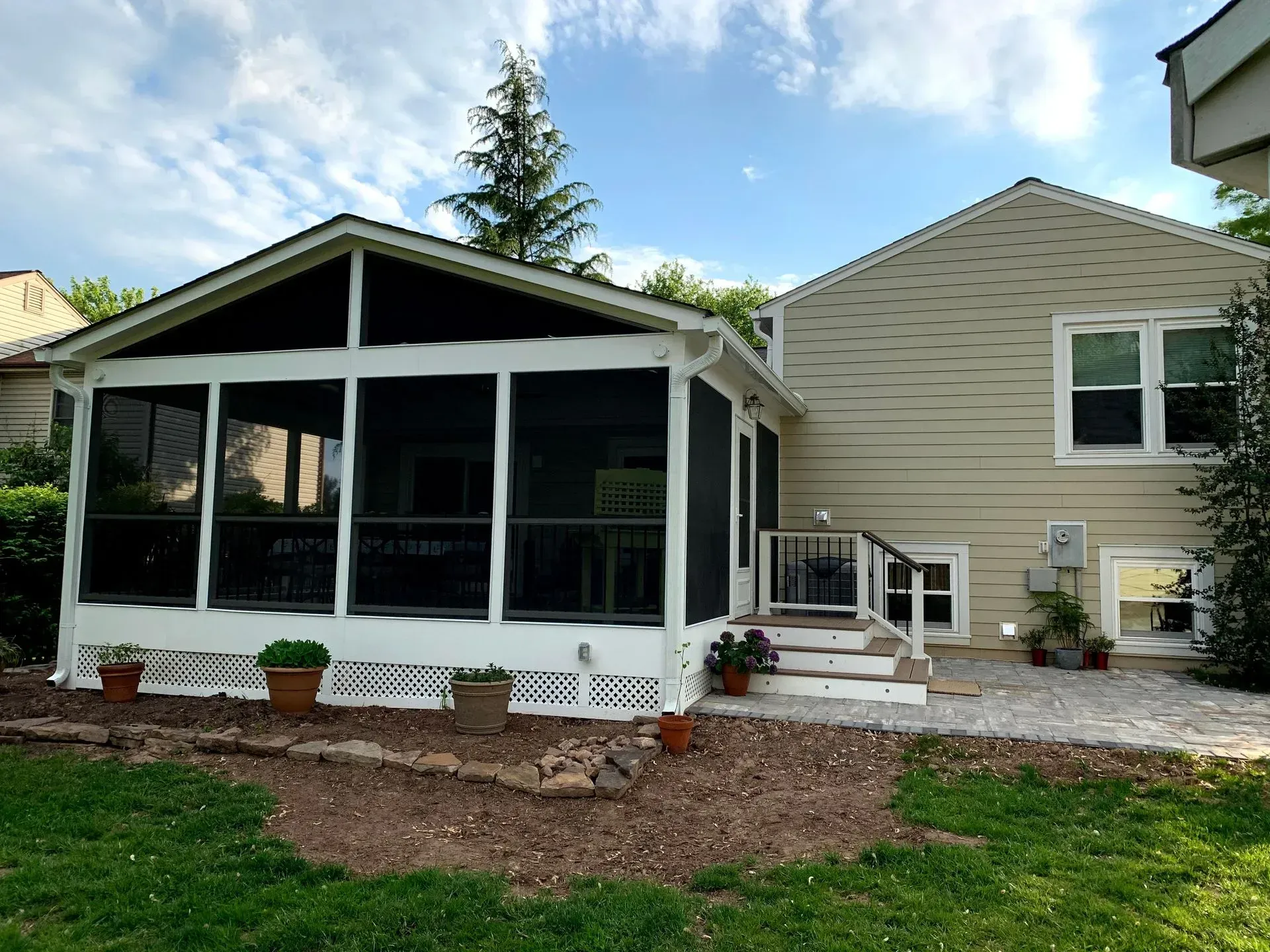 A screened in porch is in the backyard of a house.