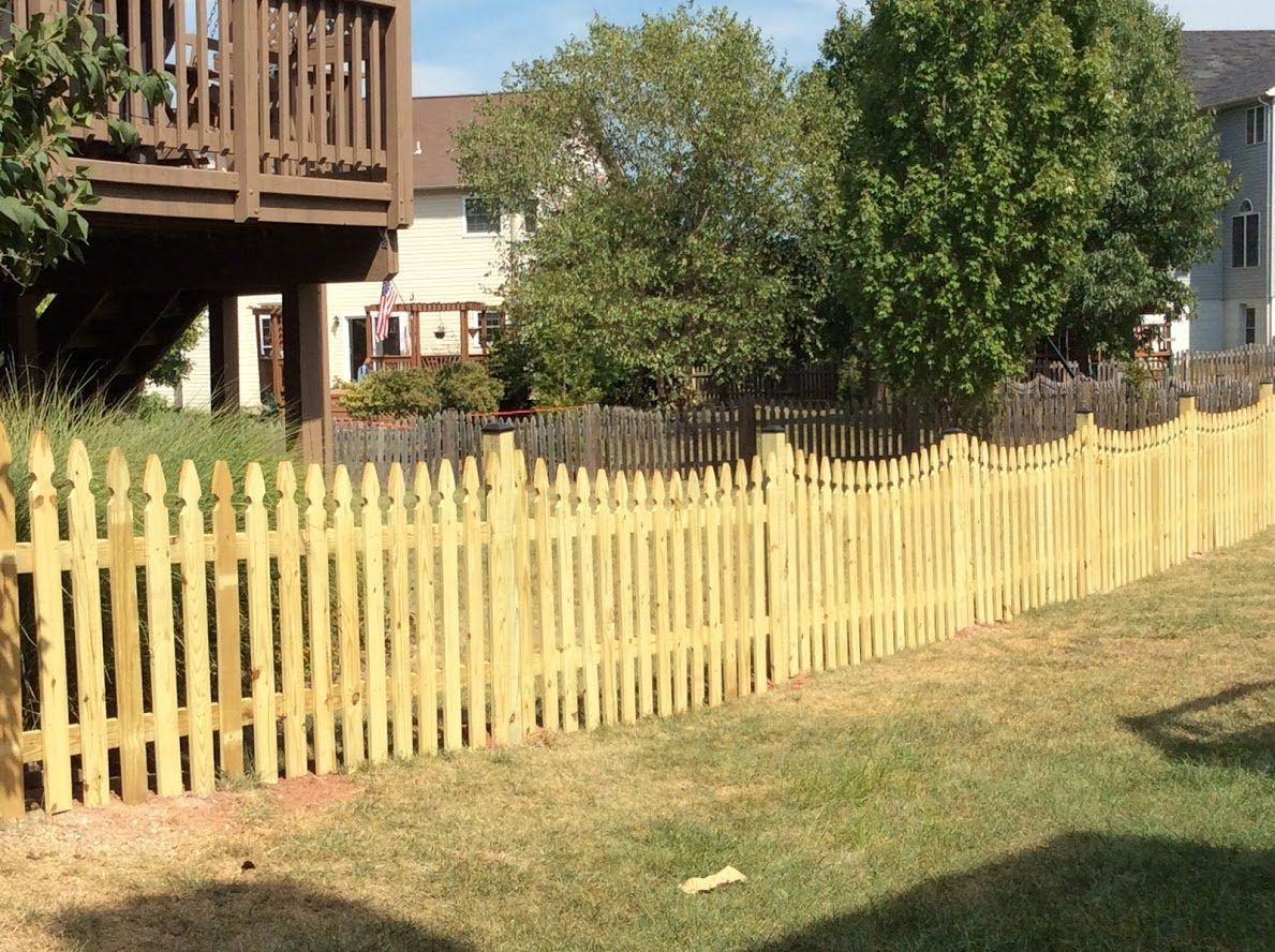 A wooden picket fence with a deck in the background