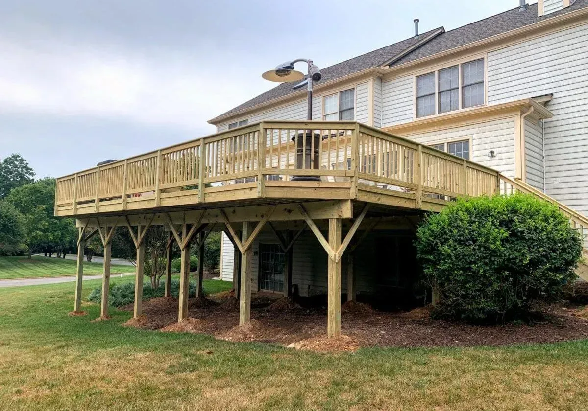 A large wooden deck is sitting in front of a large white house.