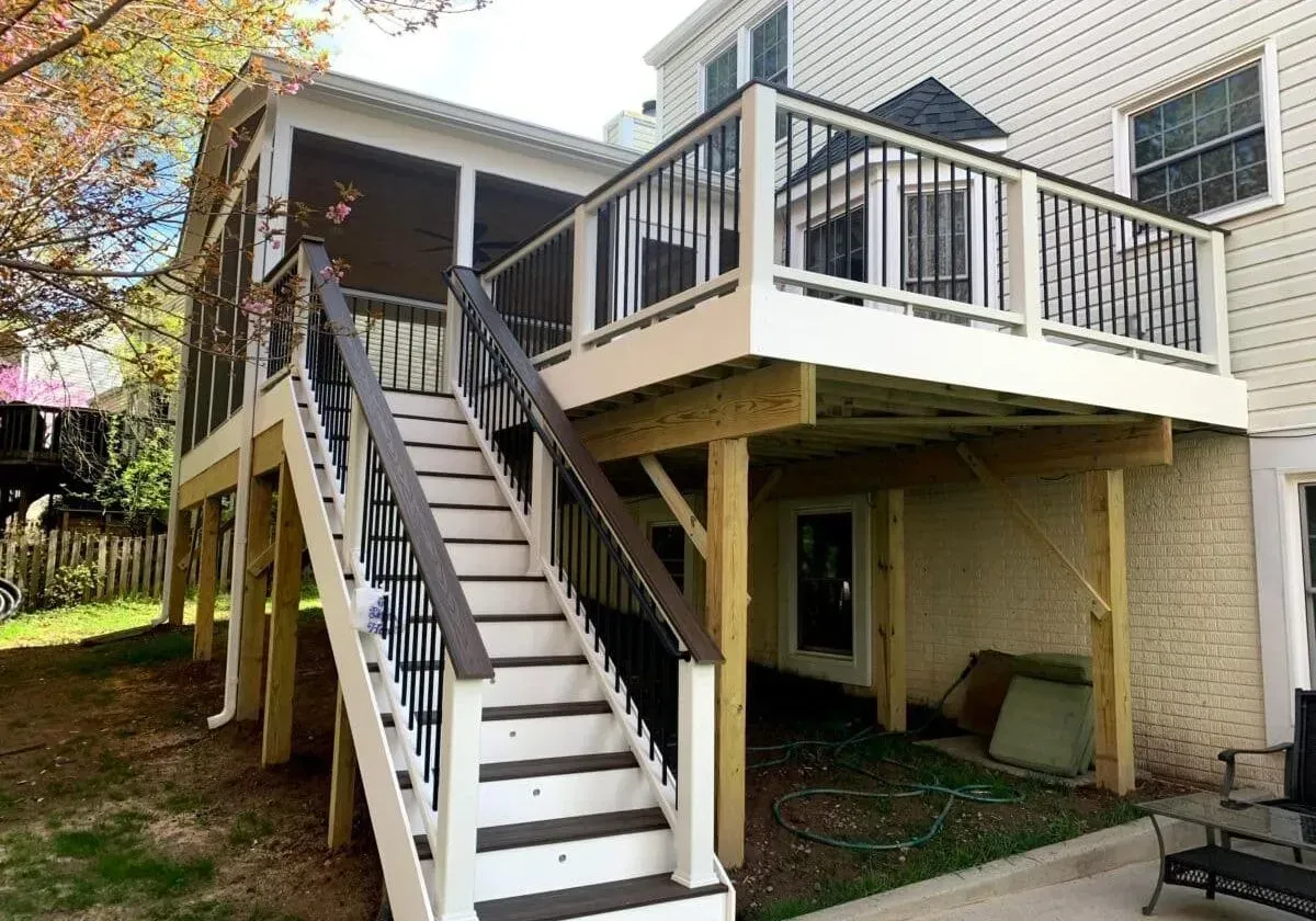 A deck with stairs leading up to it and a screened in porch.