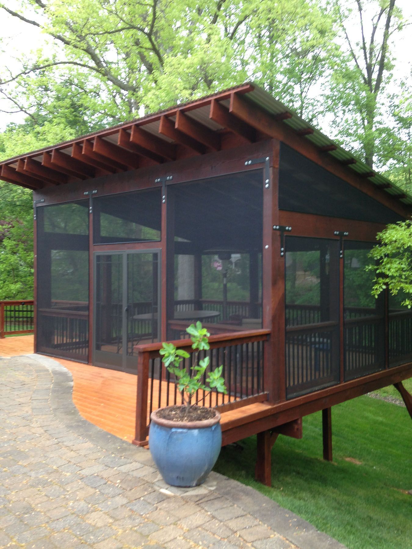 A screened in porch with a blue potted plant in front of it