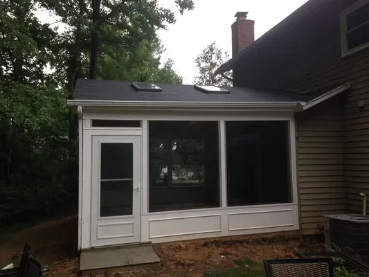 A screened in porch is attached to the side of a house.