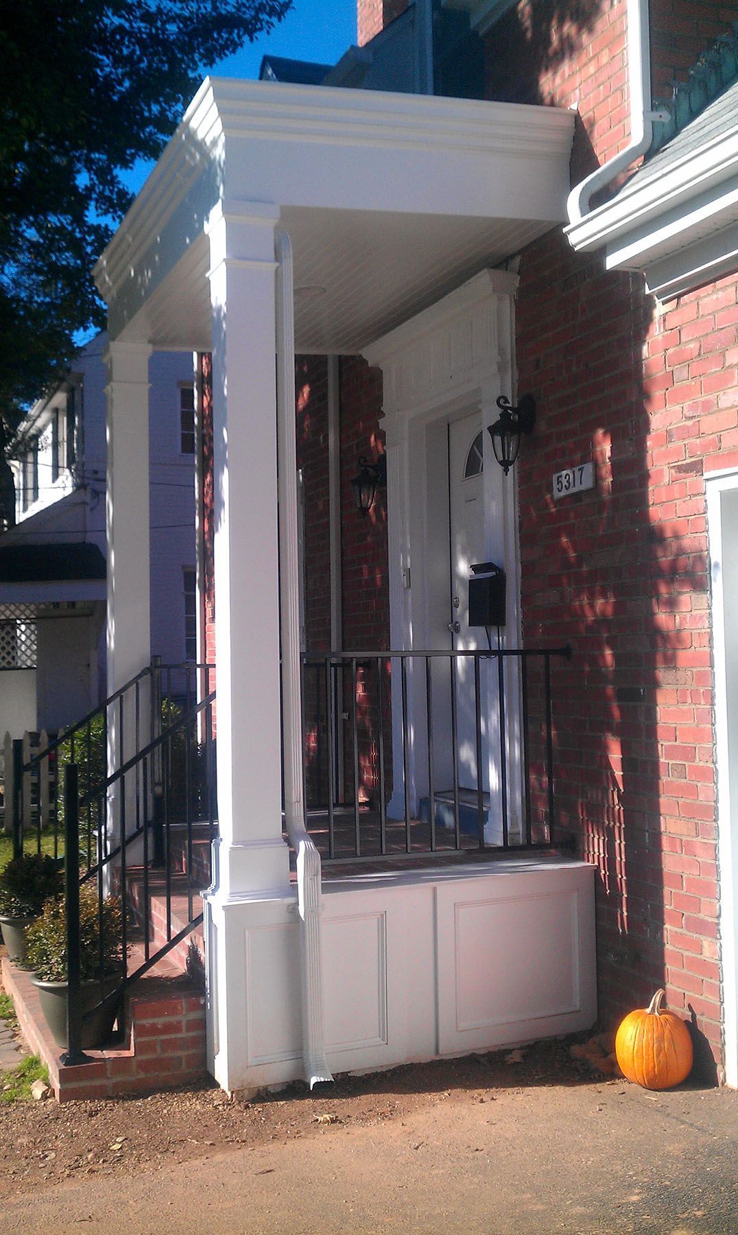 A brick house with a porch and a pumpkin in front of it