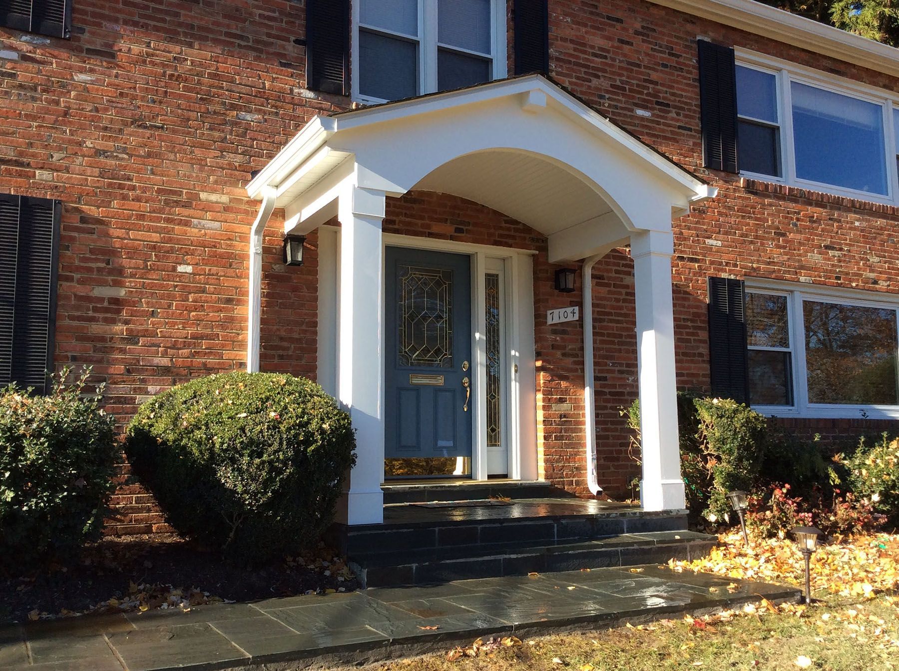 A brick house with a blue door and a white porch