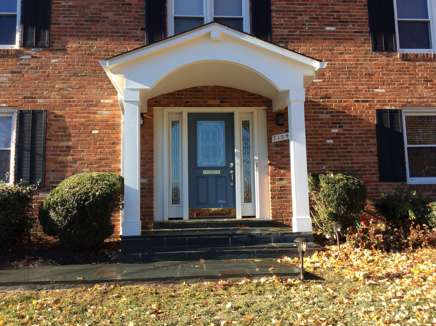 A brick house with a porch and a blue door