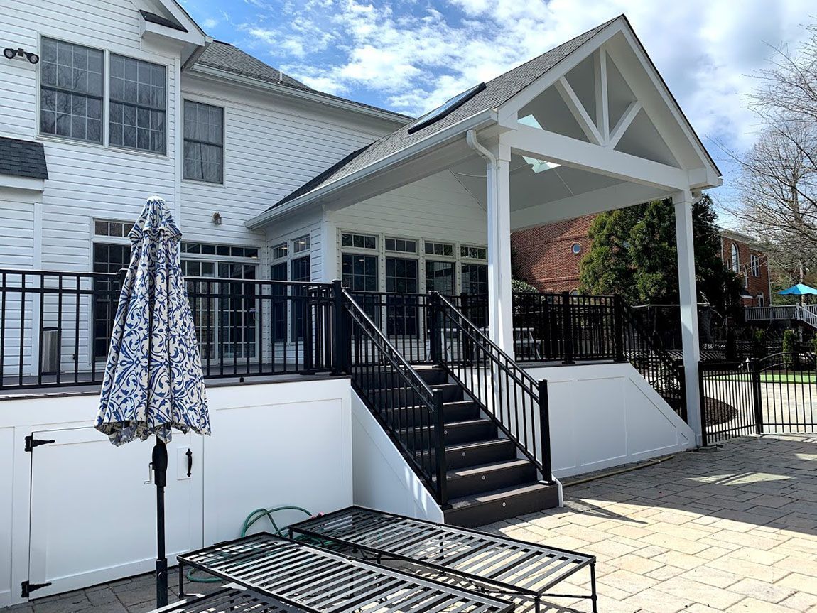 A white house with a large porch and stairs leading up to it.
