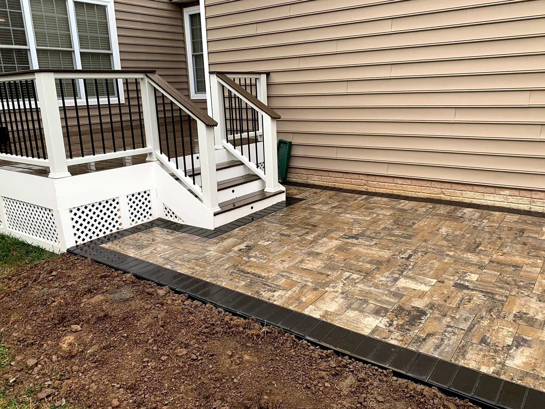 A patio with stairs leading up to a deck in front of a house.