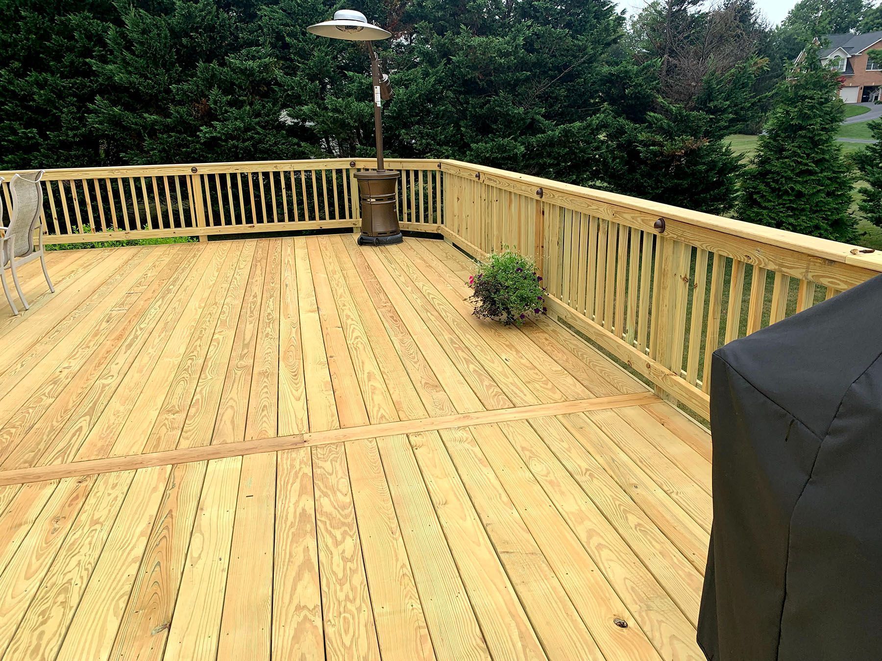 A wooden deck with a grill and a heater on it.