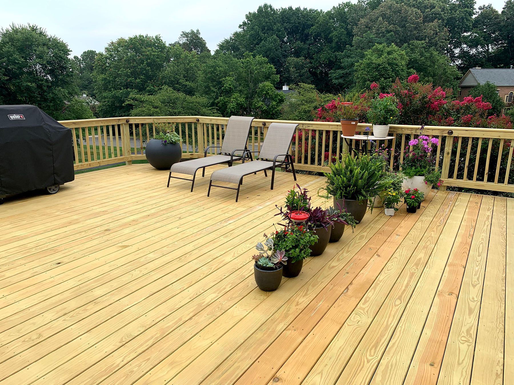 A wooden deck with chairs and potted plants on it.