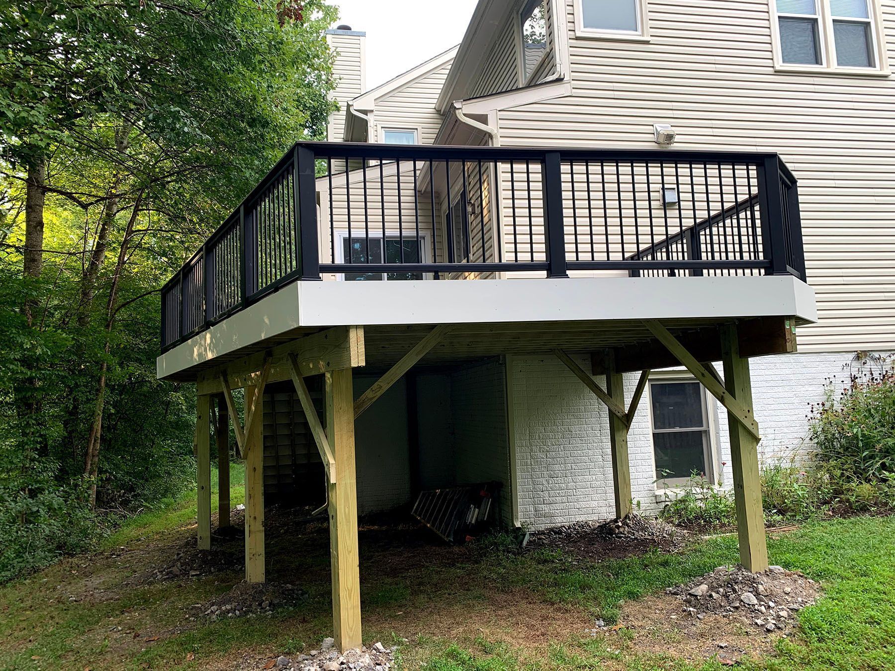 A wooden deck with a black railing is in front of a house.