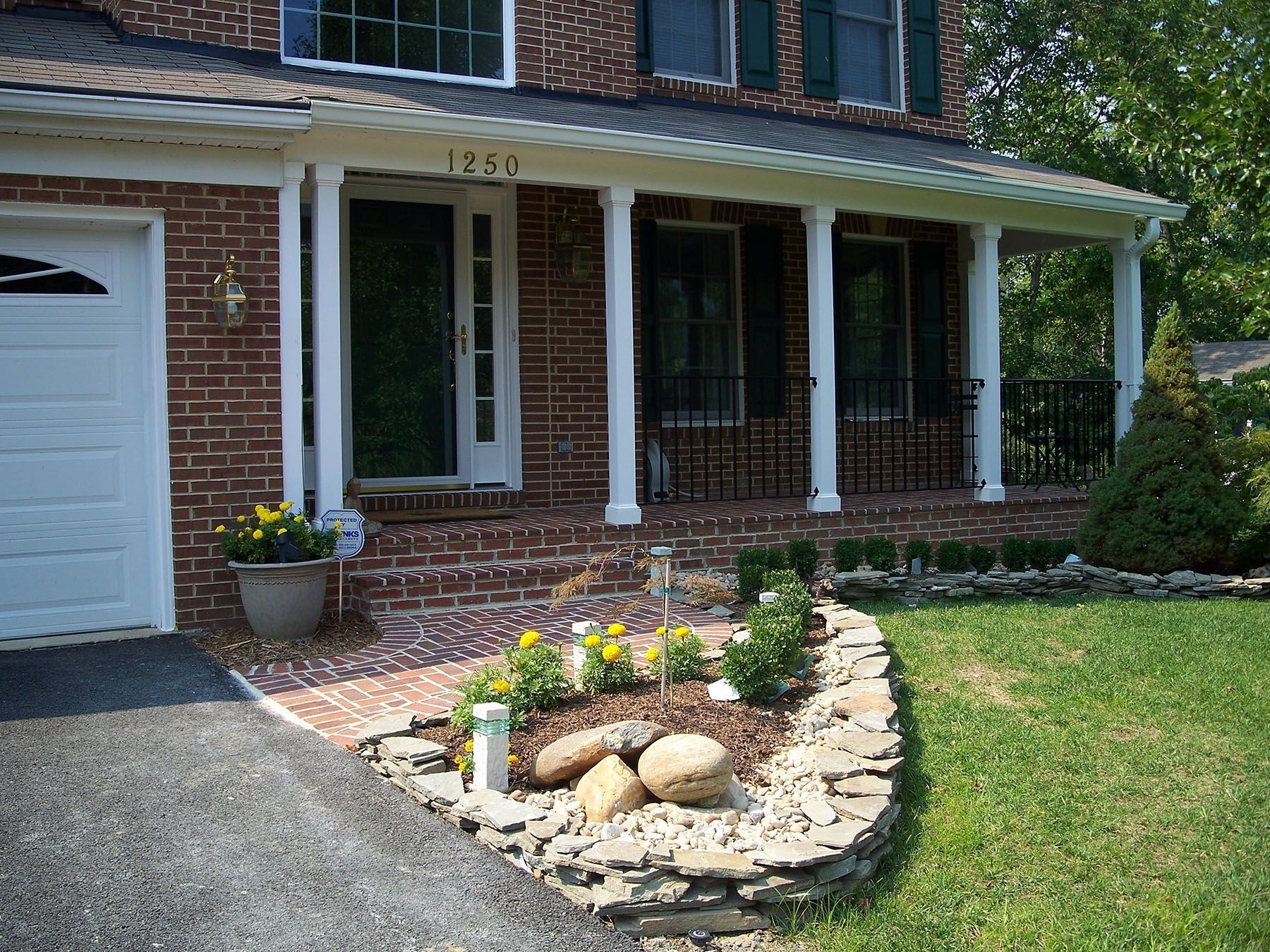 A brick house with a porch and a white garage door