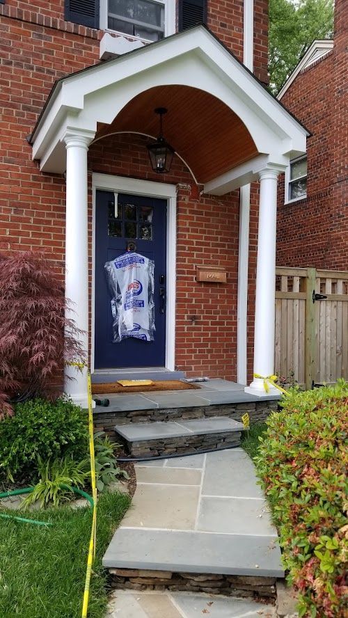 A brick house with a porch and steps leading to it.