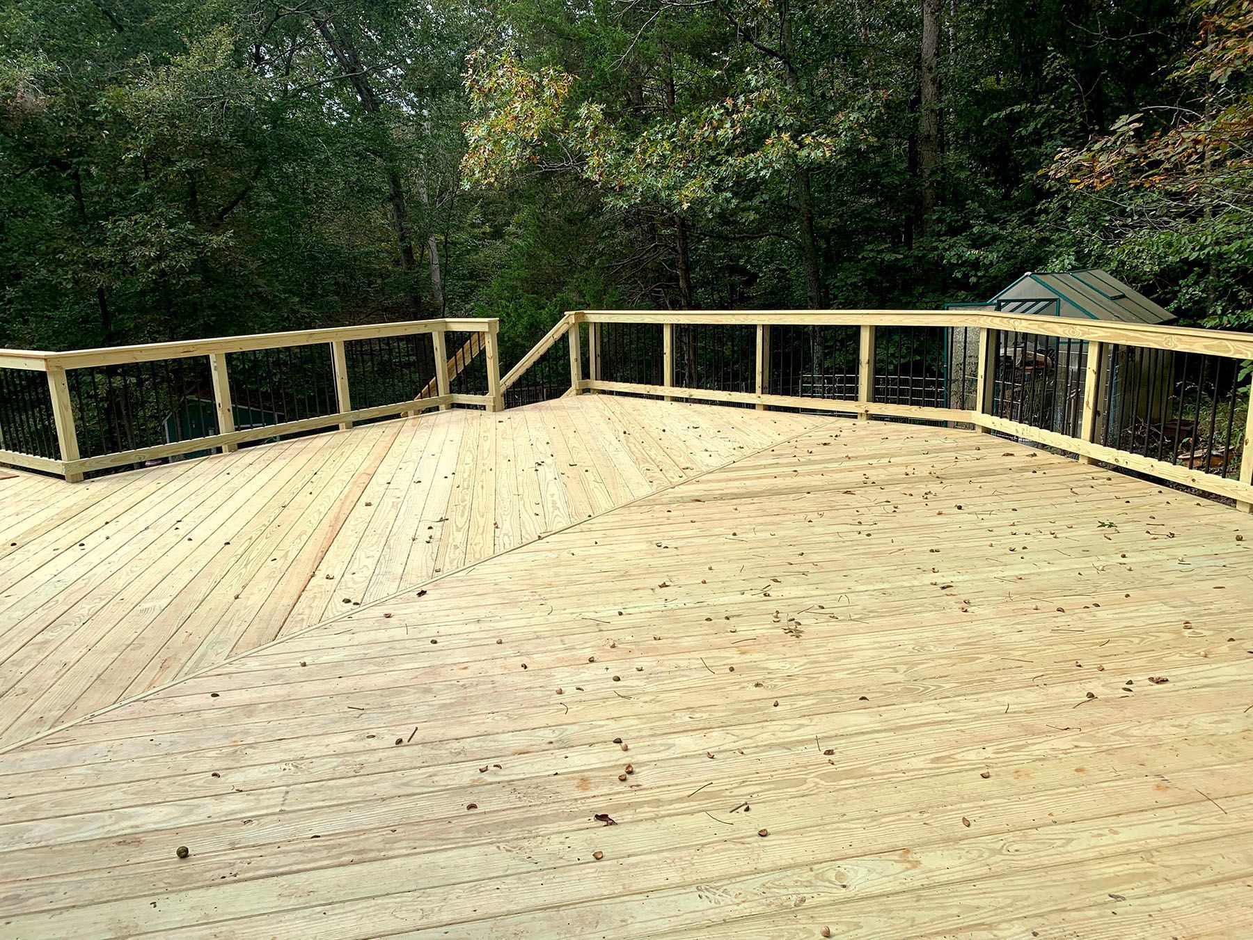 A wooden deck with a railing and trees in the background.