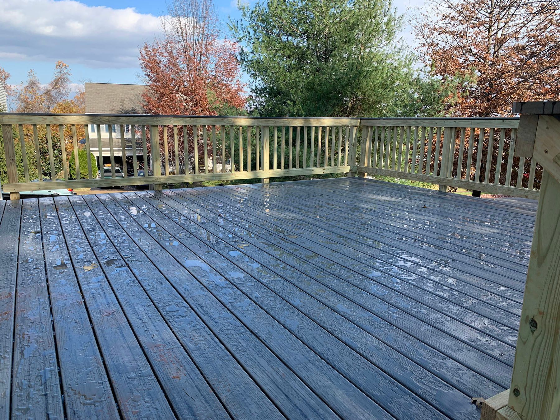 A wooden deck with a railing and trees in the background.