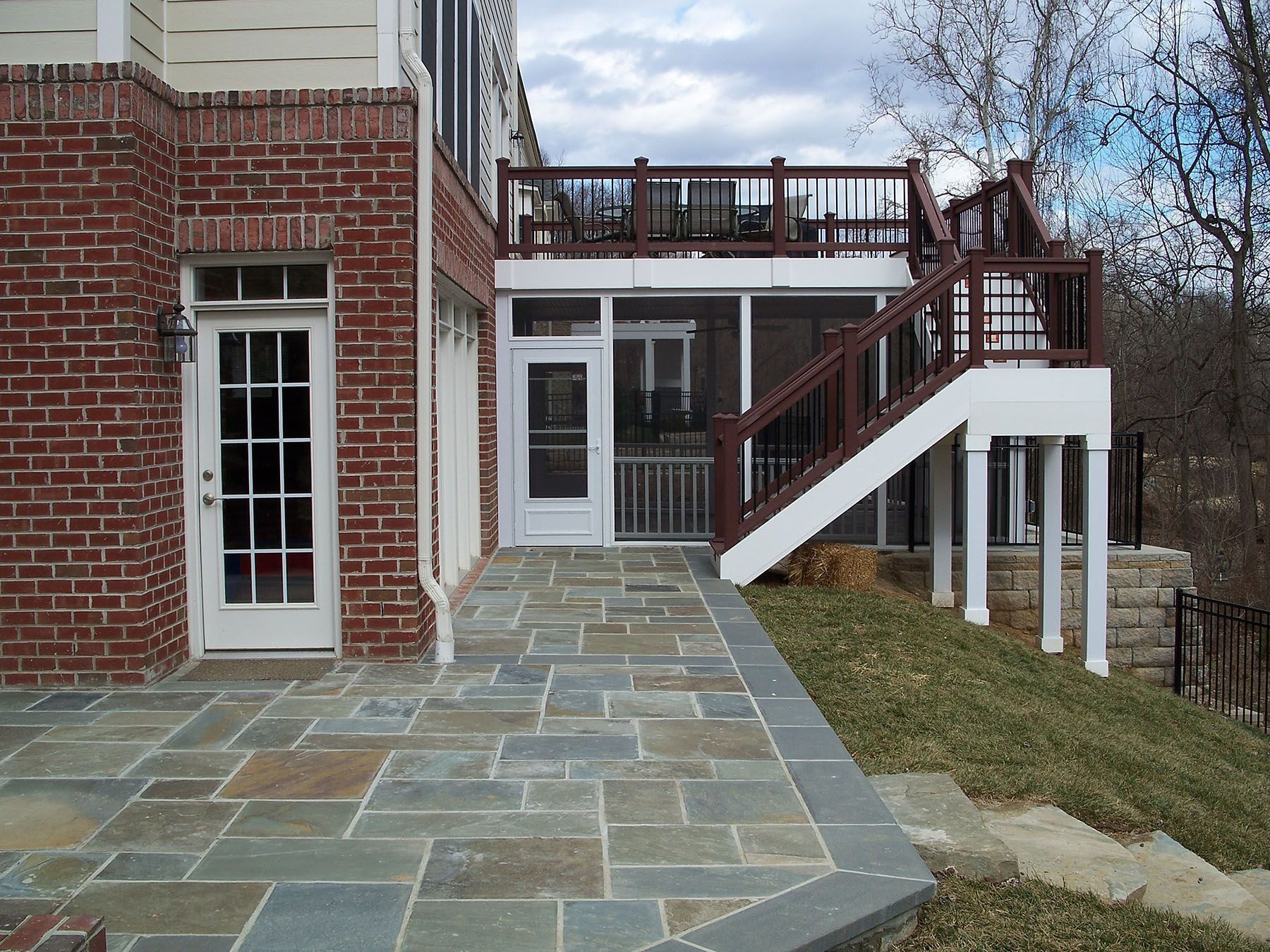 A brick house with a screened in porch and stairs