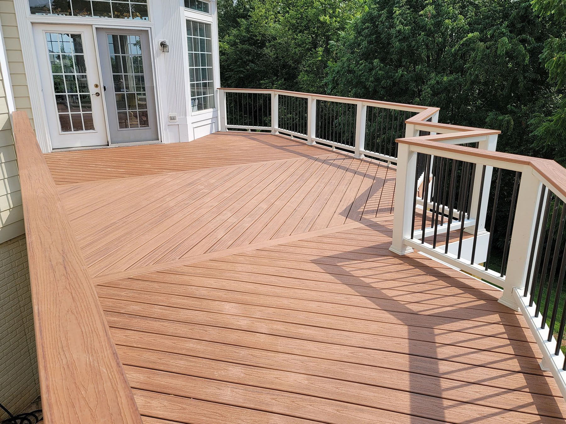 A wooden deck with a white railing and sliding glass doors