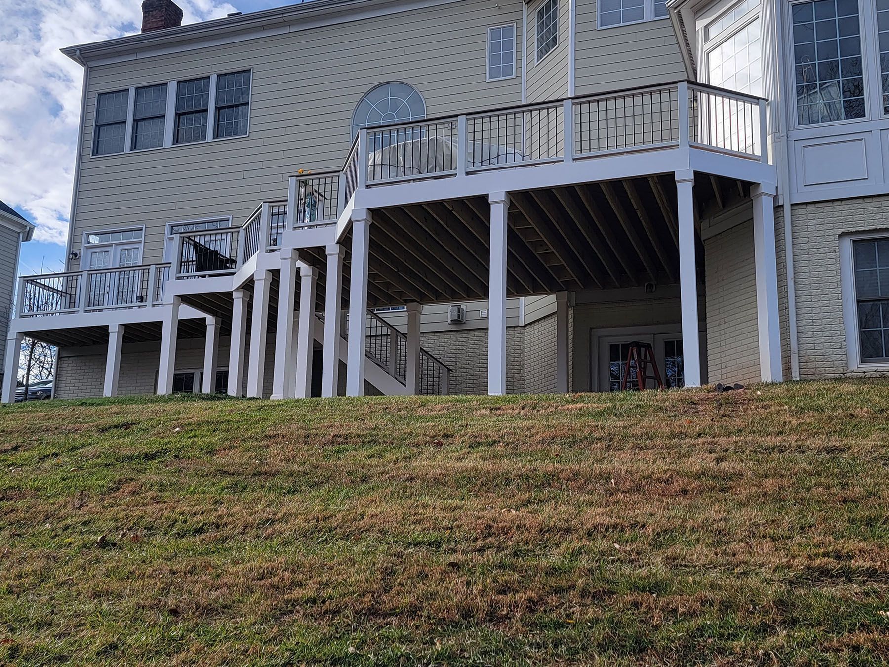 The back of a house with a large deck and stairs.