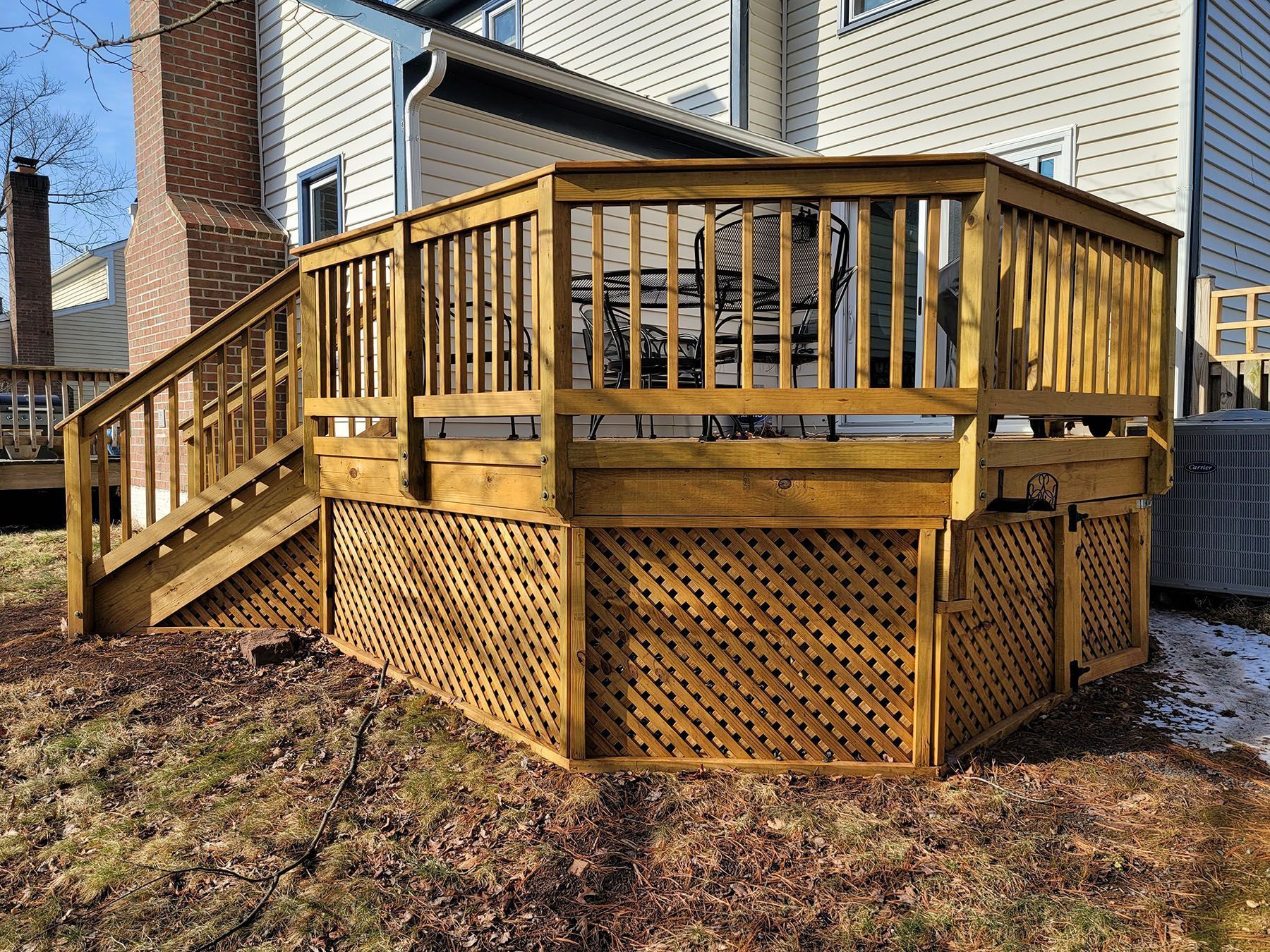 A wooden deck with stairs leading up to it in front of a house.