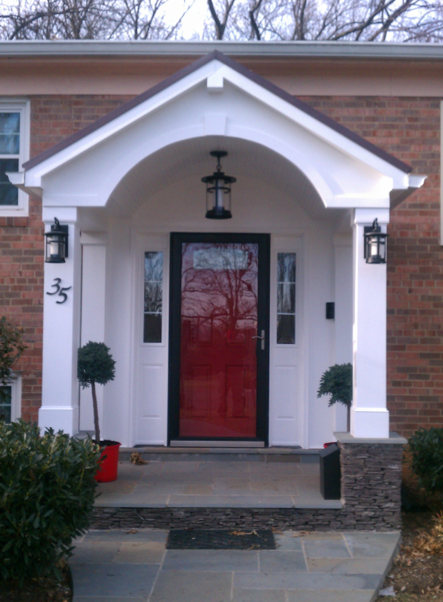 The front door of a brick house has a red door