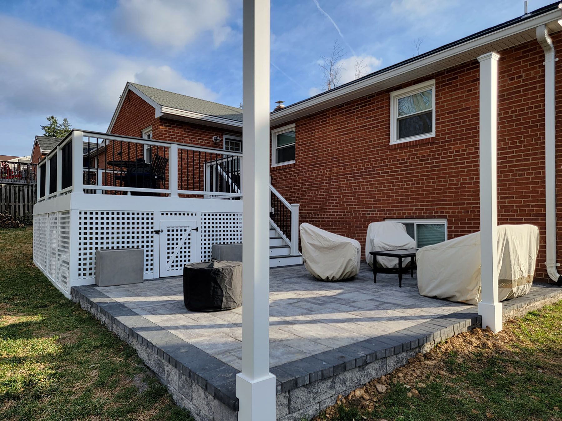 A brick house with a deck and patio in front of it.