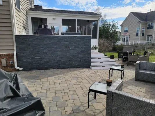 A patio with a screened in porch and a brick wall.