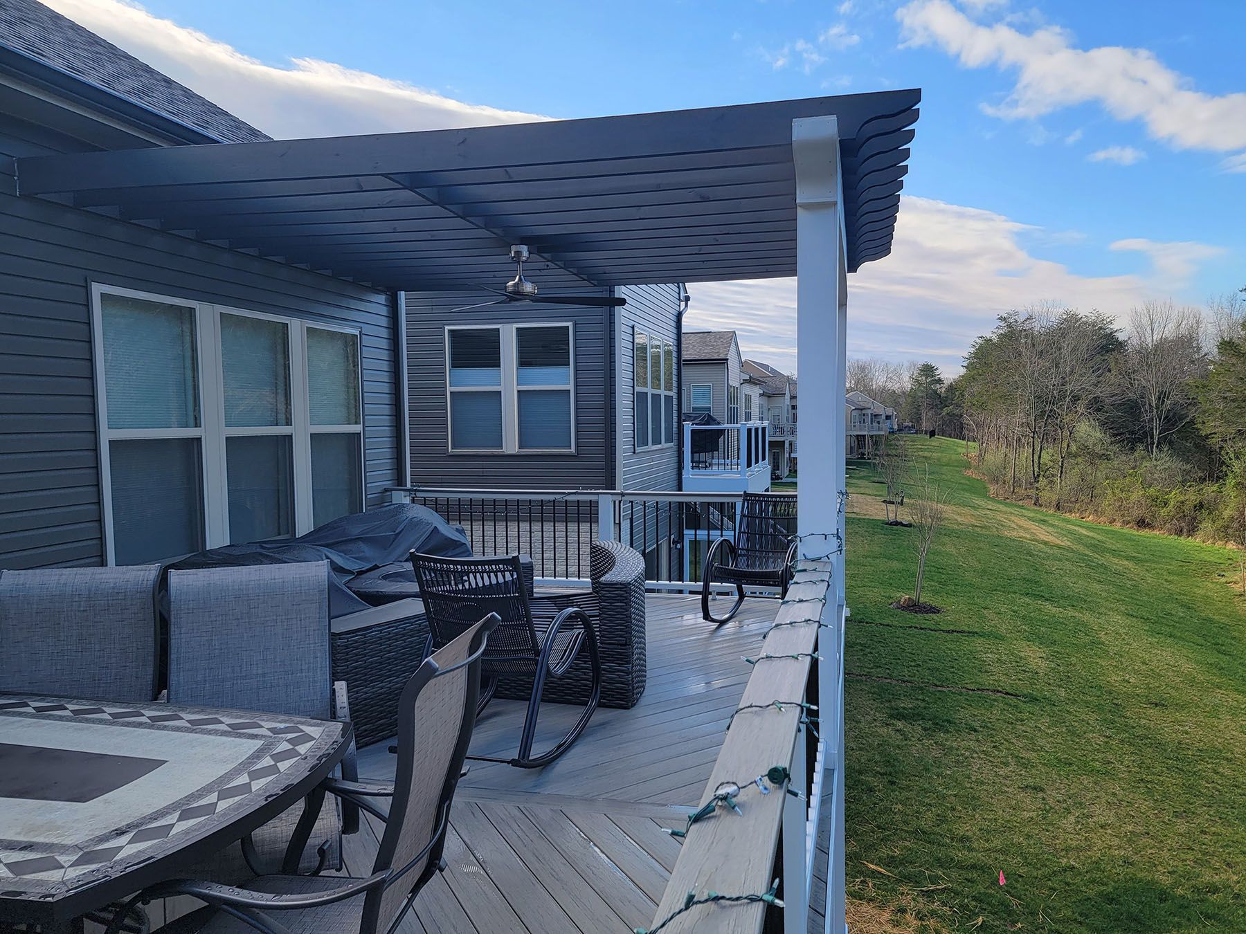 A deck with a table and chairs under a pergola.