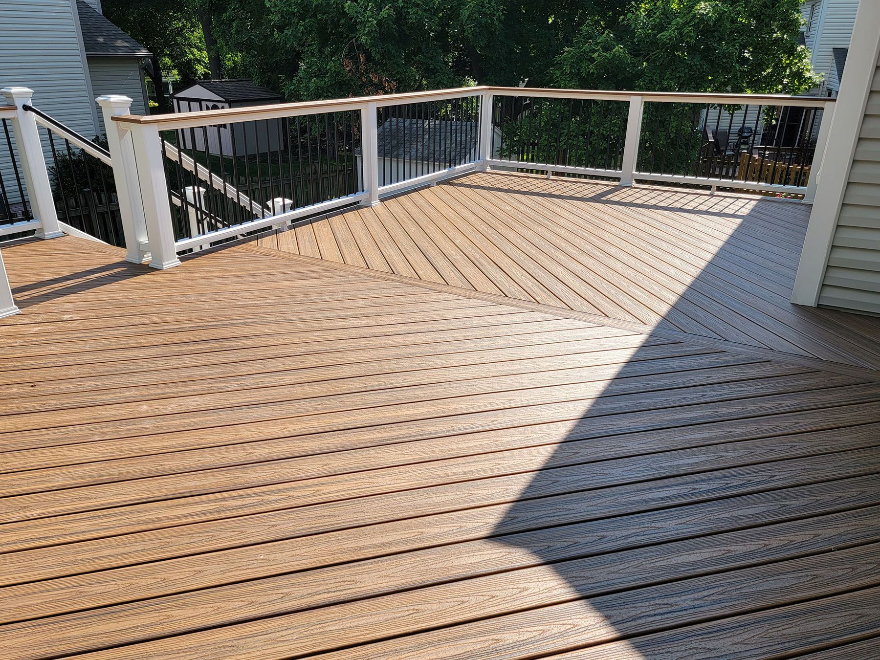 A wooden deck with a white railing and stairs leading up to it.