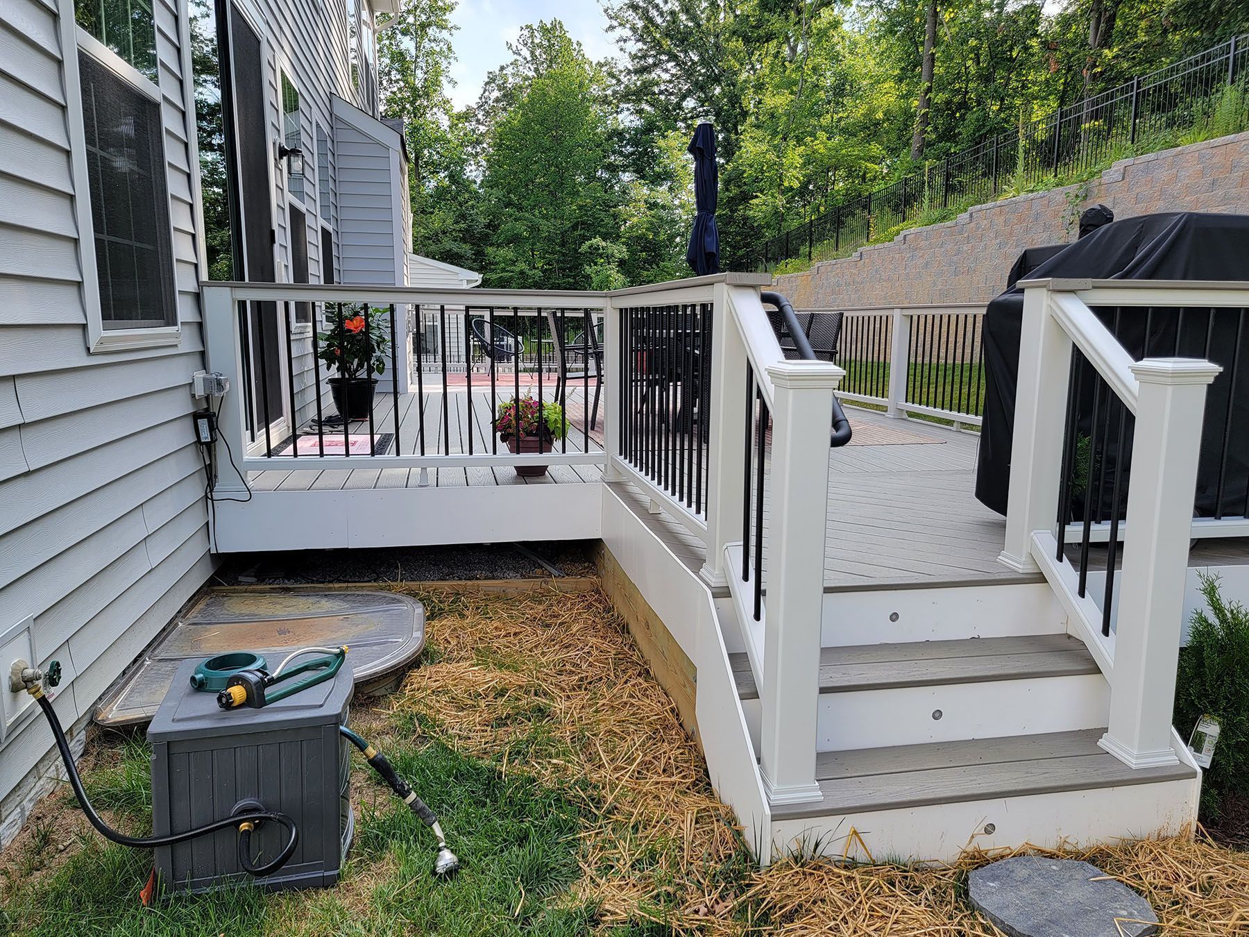 A white house with a deck and stairs in front of it.