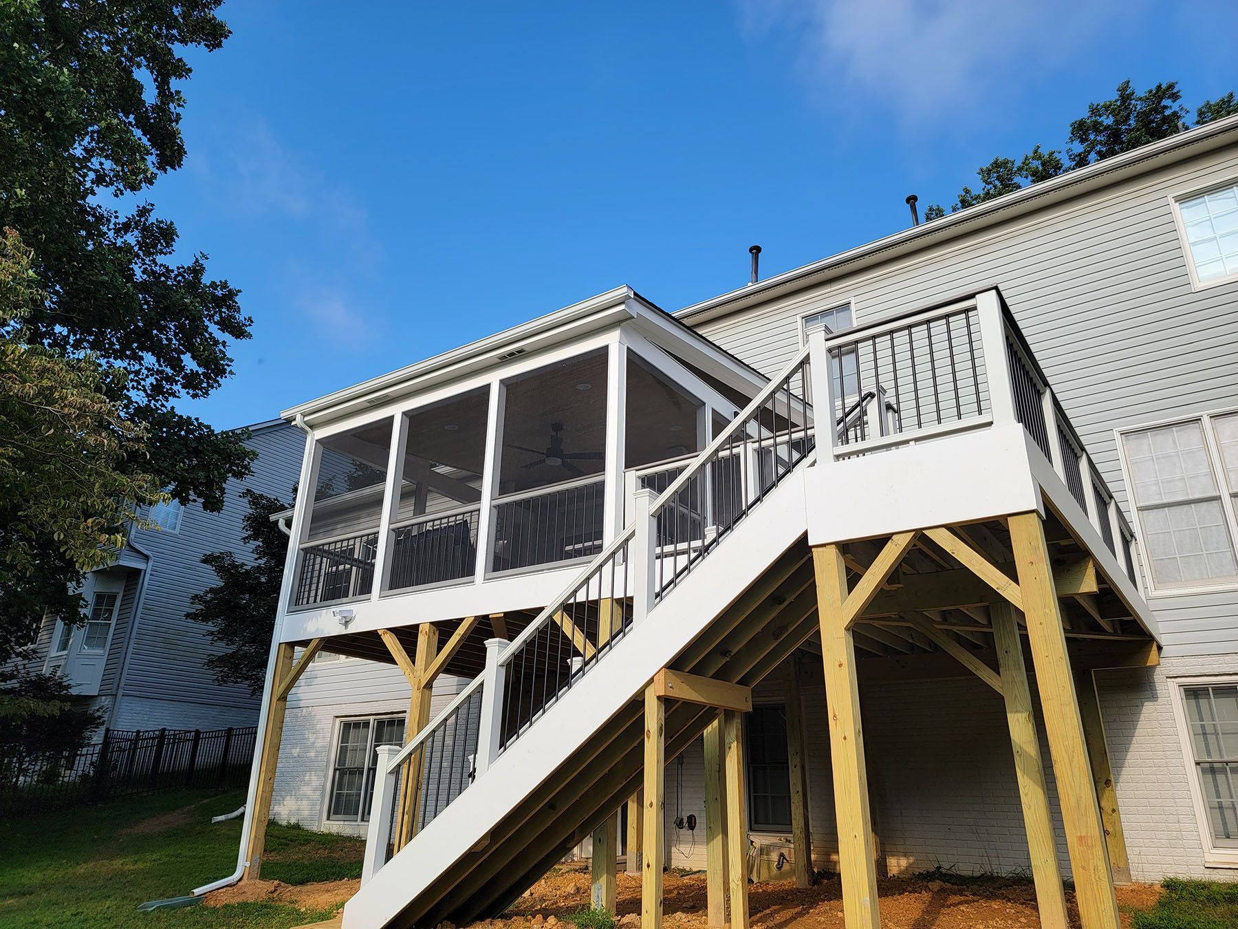 A white house with a screened in porch and stairs.