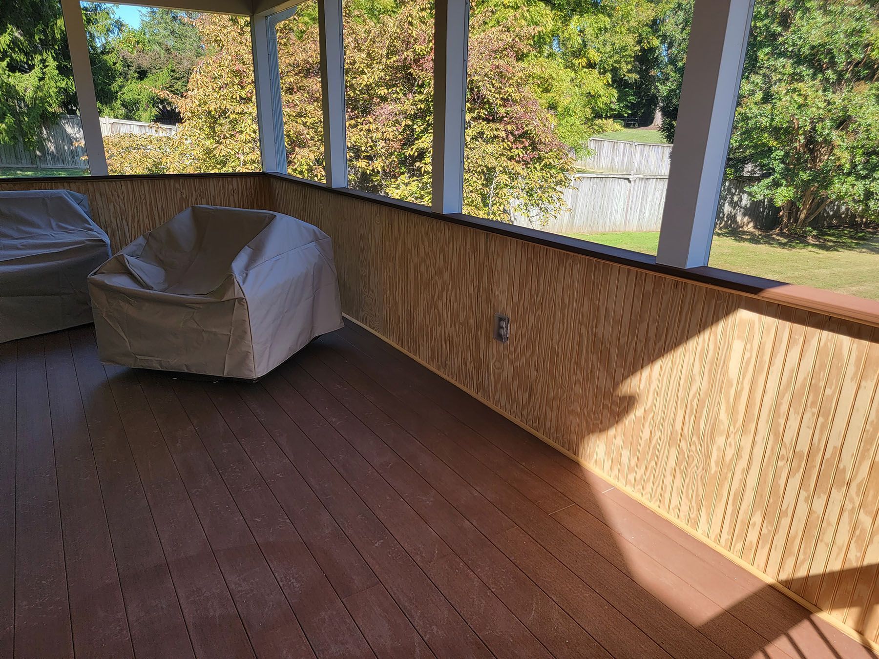A screened in porch with a chair and a chair cover.