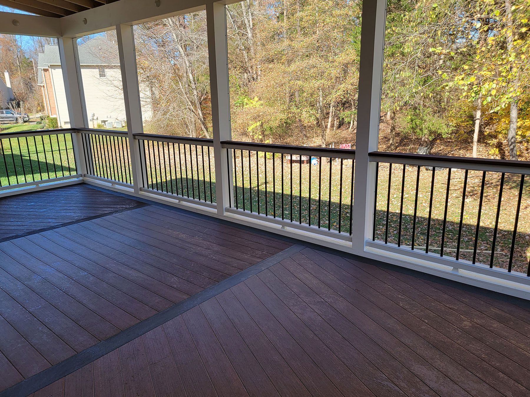 A large covered porch with a wooden floor and a metal railing.