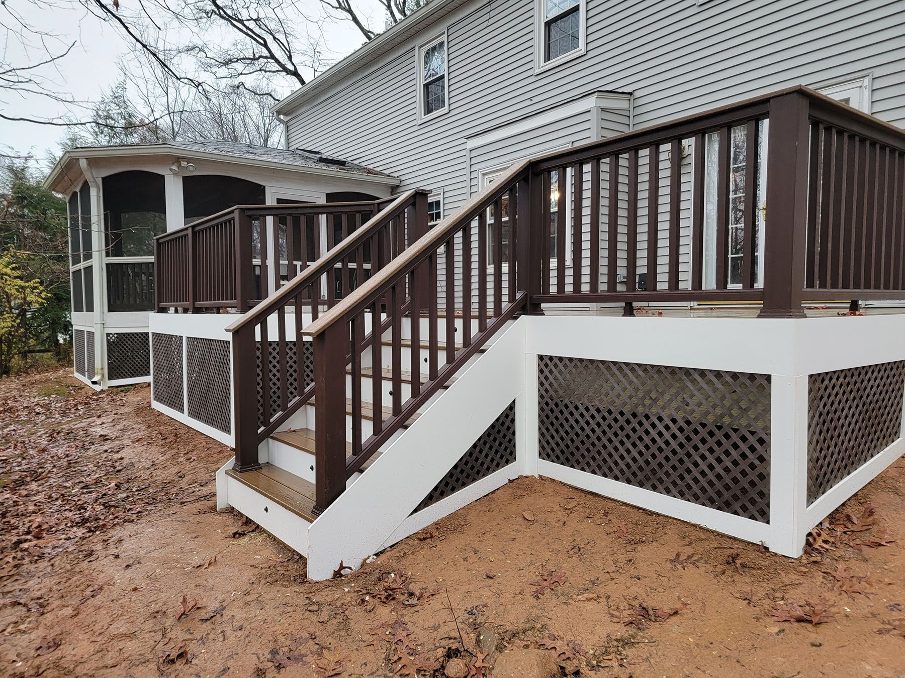 A deck with stairs and a screened in porch next to a house.