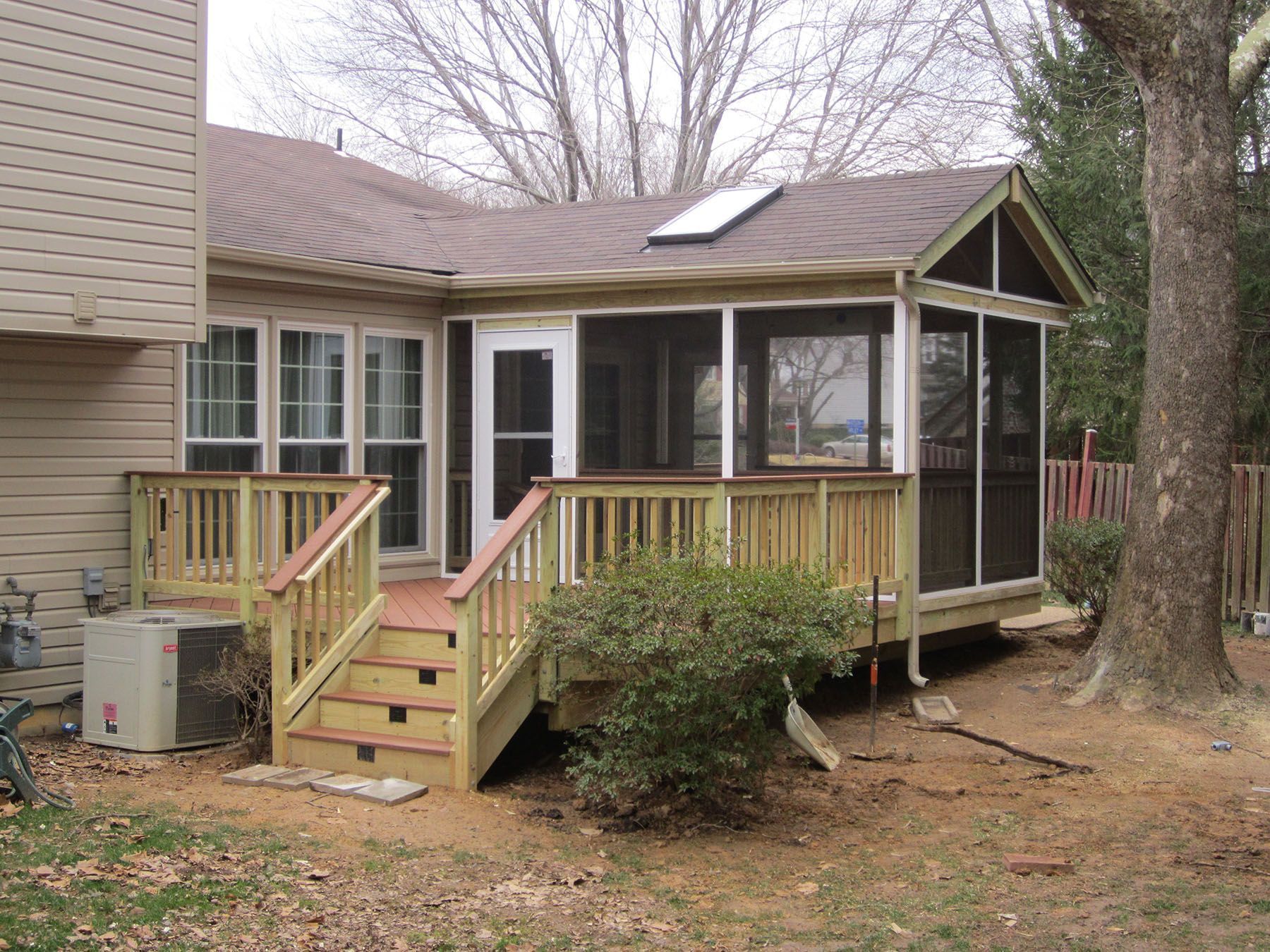 A screened in porch in the backyard of a house