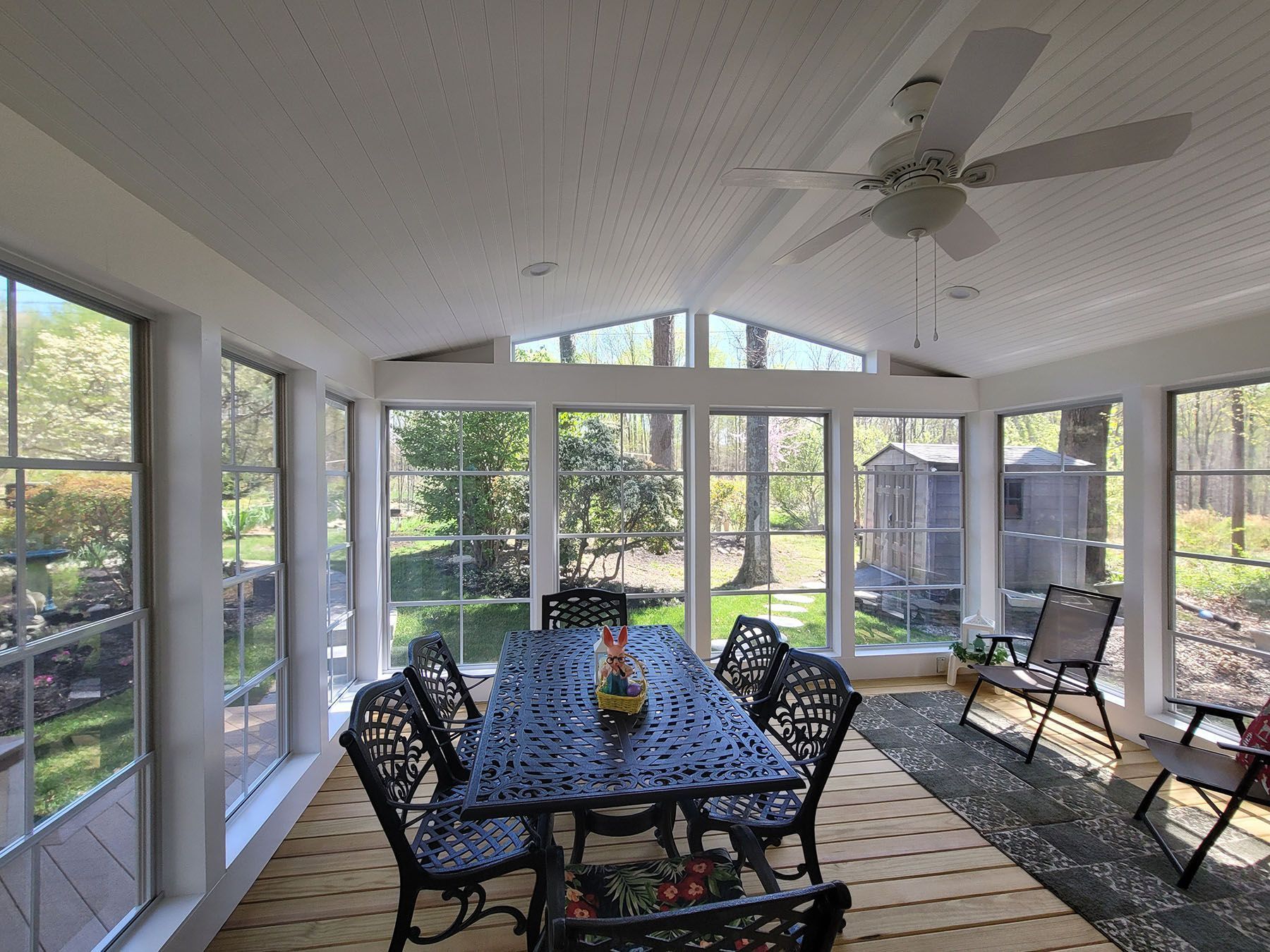 A sun room with a table and chairs and a ceiling fan