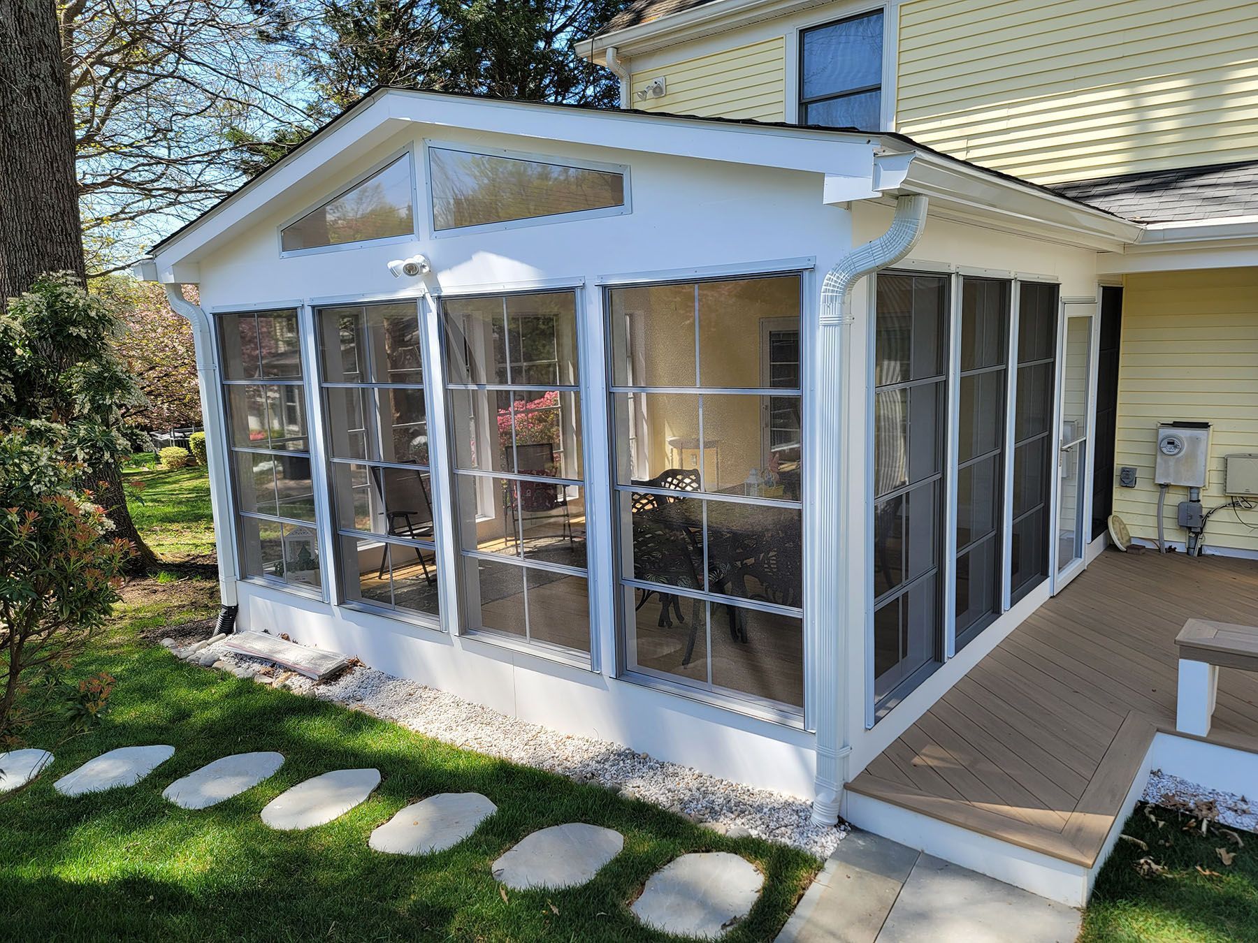 A screened in porch in the backyard of a house.